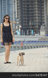 beautiful happy young woman in black dress with cute small dog puppy have fun on street