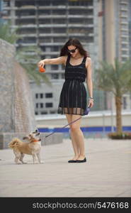 beautiful happy young woman in black dress with cute small dog puppy have fun on street