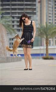 beautiful happy young woman in black dress with cute small dog puppy have fun on street