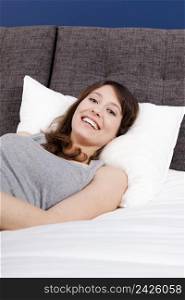 Beautiful happy young woman in pajama and lying on the bed