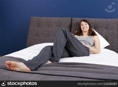 Beautiful happy young woman in pajama and lying on the bed