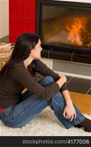 Beautiful happy young woman sitting looking in home fireplace