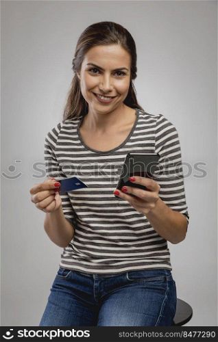 Beautiful happy young woman sitting on a bench and shopping online