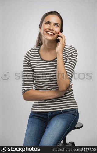 Beautiful happy young woman sitting on a bench making a phone call
