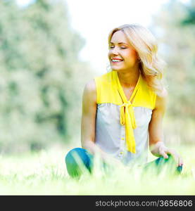 Beautiful happy young woman sitting on grass