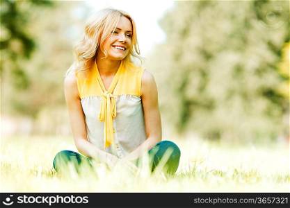 Beautiful happy young woman sitting on grass