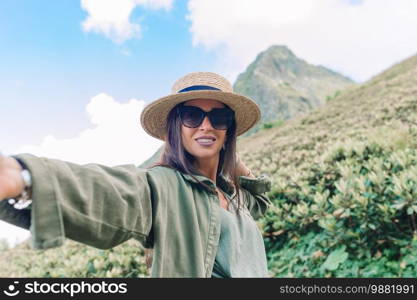 Beautiful happy young woman taking selfie on a lift in the mountains in the ropeway. Beautful landscape. Beautiful happy young woman in mountains in the background of fog