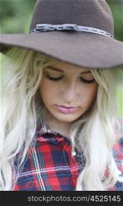 Beautiful healthy young woman outdoors wearing big floppy hat and a checked shirt