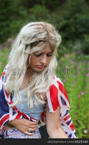 Beautiful healthy young woman outdoors wearing casual outfit wrapped in a union jack flag