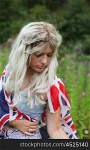 Beautiful healthy young woman outdoors wearing casual outfit wrapped in a union jack flag