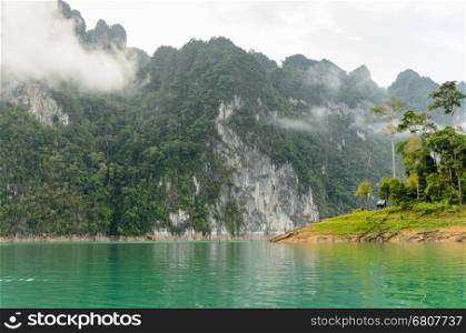 Beautiful high mountains and green lake in morning at Ratchaprapha Dam, Khao Sok National Park, Surat Thani Province, Thailand