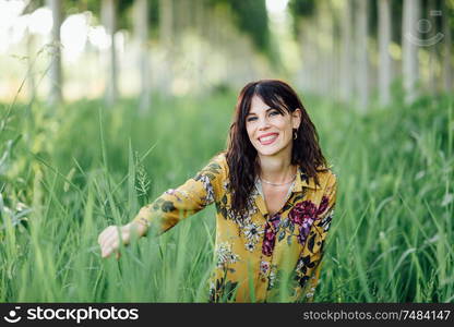 Beautiful hiker young woman, wearing flowered dress, hiking in the countryside.. Young woman, wearing flowered dress, between trees.