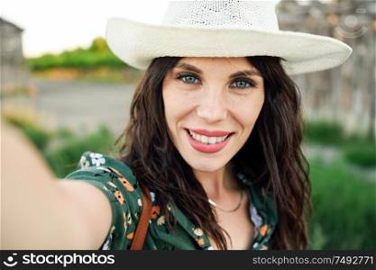 Beautiful hiker young woman, wearing flowered shirt, taking a selfie photograph outdoors. Hiker young woman taking a selfie photograph outdoors