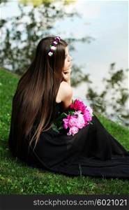 Beautiful hippy bohemian fashion style model in beautiful lake environment. Brunette woman with flowers enjoying nature against nature background
