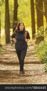 Beautiful Hispanic woman dressed in black with backpack walking alone on a forest path during the morning. Beautiful Hispanic woman dressed in black with backpack walking alone on a forest path
