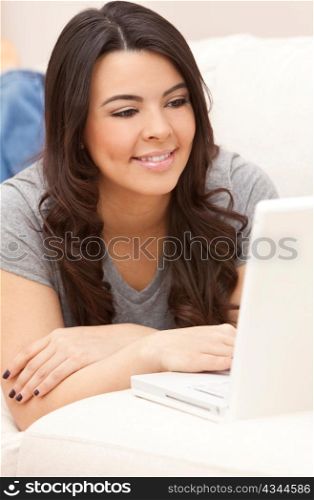 Beautiful Hispanic Woman Laying on Sofa Using Laptop Computer