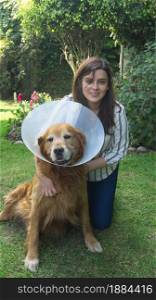 Beautiful Hispanic young woman hugging her injured Golden Retriever dog with a plastic cone on her neck in her home garden during sunset. Beautiful Hispanic young woman hugging her injured Golden Retriever dog with a plastic cone on her neck in her home garden