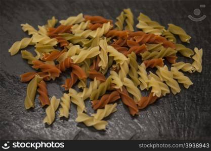 Beautiful homemade Italian pasta Fusilli from durum wheat on stone background, closeup.