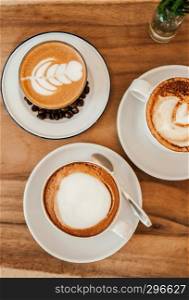 Beautiful hot Coffee Latte with nice milk form and decorating coffee beans and cups of coffee cappuccino on wood table, Top view shot