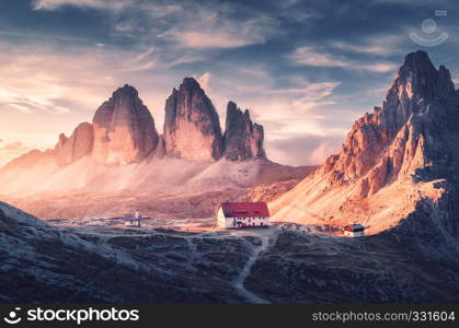 Beautiful house and church in mountain valley at sunset in autumn. Landscape with buildings, high rocks, trail, blue sky and sunlight. Mountains in Tre Cime park in Dolomites, Italy. Italian alps