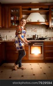 Beautiful housewife baking cookies in oven on country style kitchen