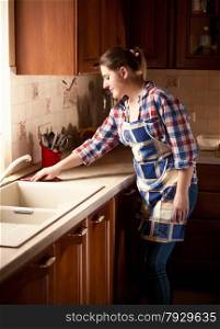 Beautiful housewife cleaning tabletop on kitchen