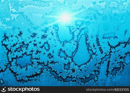 Beautiful ice pattern and bright sunlight close-up on winter window glass