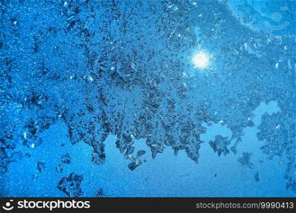 Beautiful ice pattern and sunlight on glass, blue winter texture
