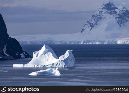 Beautiful iceberg brightly lit by sunlight swims in the dark Antarctic sea