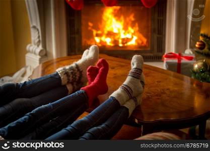 Beautiful image of family feet in woolen socks resting next to the burning fireplace