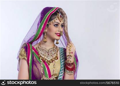Beautiful Indian bride looking away against gray background