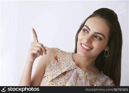 Beautiful Indian woman pointing at copy space over white background