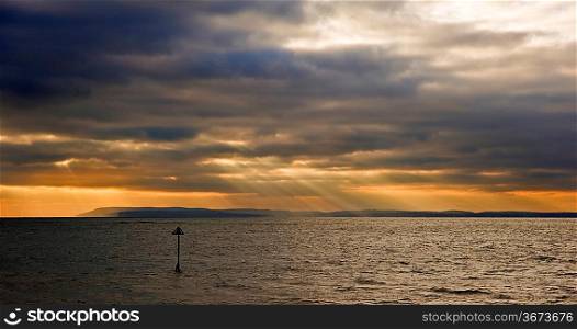 Beautiful inspirational sunset scene with sun beams over smooth sea