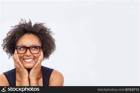 Beautiful intelligent mixed race African American girl or young woman smiling with perfect teeth, wearing glasses and looking up into white copy space