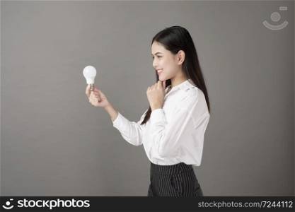 Beautiful intelligent woman is holding light bulb in studio