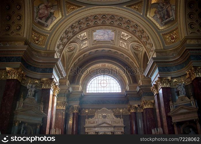 Beautiful interior of Catholic Cathedral with colorful painting on the walls and marble statues and sculptures in Budapest, Hungary.. Painting murals and frescoes inside Catholic Cathedral interior in Budapest.