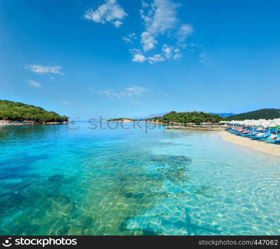 Beautiful Ionian Sea with clear turquoise water and morning summer coast view from beach (Ksamil, Albania). People unrecognizable.