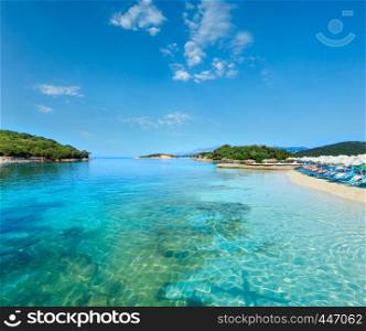 Beautiful Ionian Sea with clear turquoise water and morning summer coast view from beach (Ksamil, Albania). People unrecognizable.