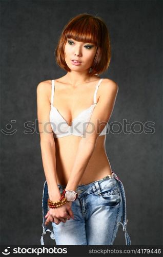 Beautiful Japanese girl in jeans over dark grey background