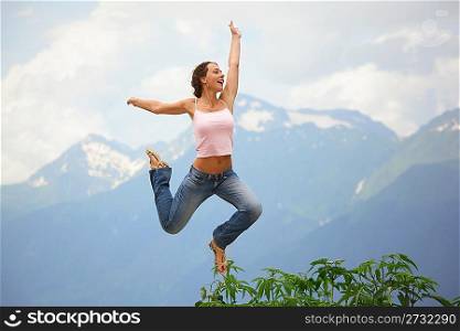 beautiful joyful woman is jumping. mountains behind her.