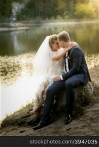 Beautiful just married couple hugging on the riverbank