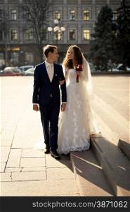 Beautiful just married couple walking on street at sunny day
