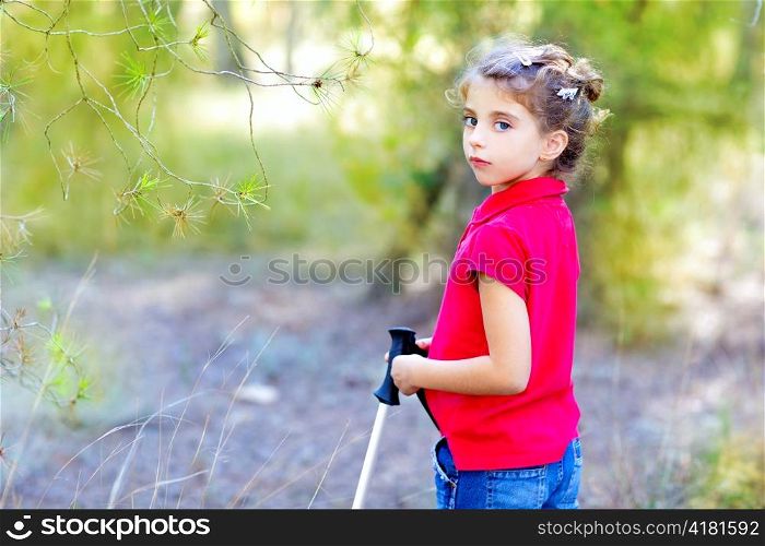 Beautiful kid girl in park forest with trekking pole