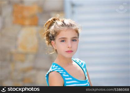 Beautiful kid girl portrait in blue with stones and door in blur background