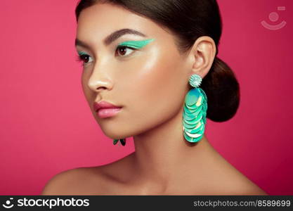 Beautiful Korean Woman with Large Turquoise Earrings. Perfect Makeup and Elegant Hairstyle. Turquoise Make-up Arrows and Pink Lipstick