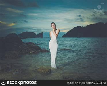 Beautiful lady in a white dress on a rocky shore