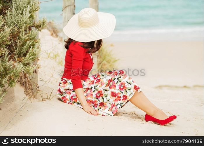 Beautiful lady in red sitting near the sea in retro style.Local focus on the woman