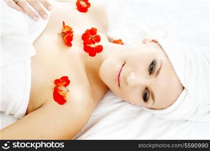 beautiful lady with red flower petals in spa