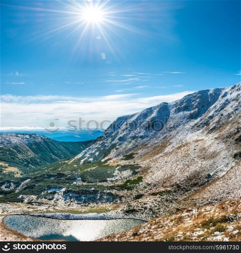 Beautiful lake in the winter mountains. Landscape with sun and snow