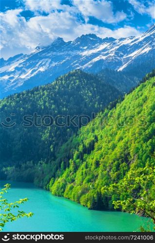 Beautiful Lake Ritsa in the Caucasus Mountains. Green mountain hills, blue sky with clouds. Spring landscape. Beautiful Lake Ritsa in the Caucasus Mountains. Green mountain hills, blue sky with clouds. Spring landscape.